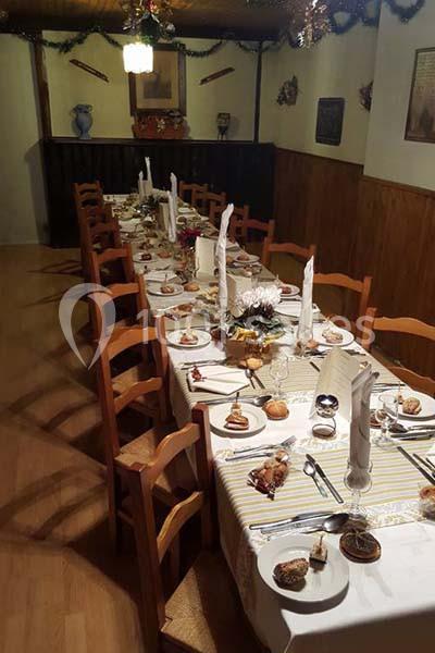 Table longue dressée pour un repas, avec nappes, serviettes pliées, assiettes, verres et décorations festives.