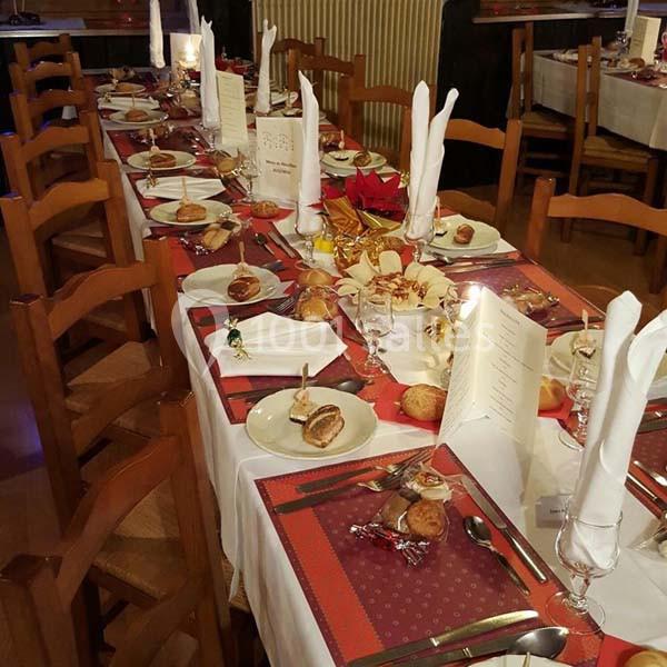 Table dressée pour un repas festif, avec nappes blanches, serviettes pliées, assiettes, couverts et décorations.