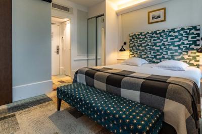 Chambre lumineuse avec un lit double, une fenêtre ouverte sur l'extérieur et un tableau accroché au mur.