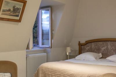 Chambre lumineuse avec un lit double, une fenêtre ouverte sur l'extérieur et un tableau accroché au mur.