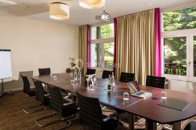Salle lumineuse avec une grande table dressée, plafond végétalisé, canapés colorés et équipements de détente.