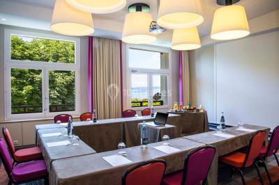 Salle lumineuse avec une grande table dressée, plafond végétalisé, canapés colorés et équipements de détente.