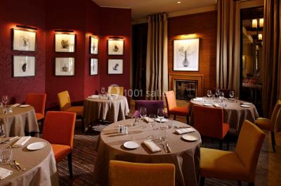 Salle lumineuse avec une grande table dressée, plafond végétalisé, canapés colorés et équipements de détente.