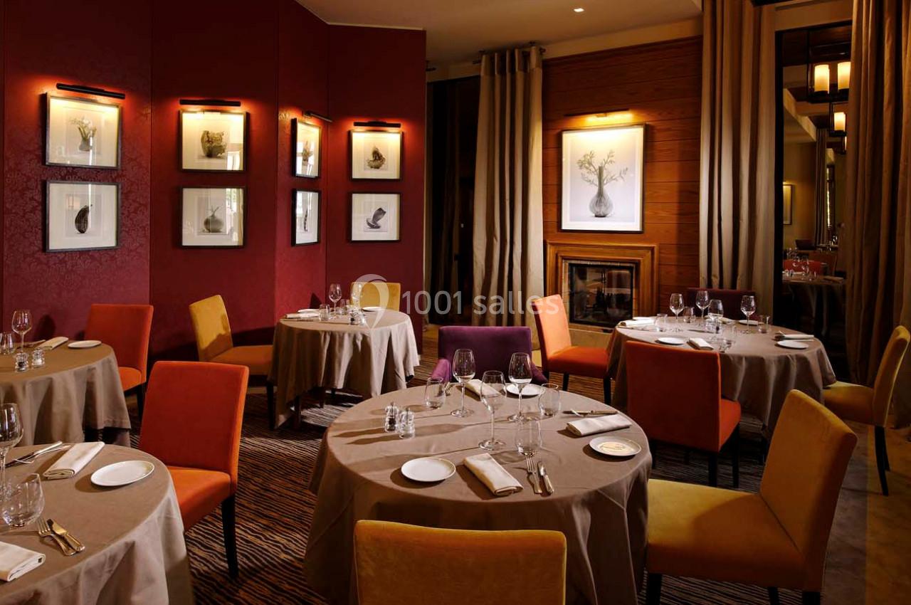 Salle de restaurant élégante avec tables dressées, chaises colorées, éclairage chaleureux et décorations murales.