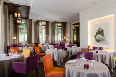 Salle lumineuse avec une grande table dressée, plafond végétalisé, canapés colorés et équipements de détente.