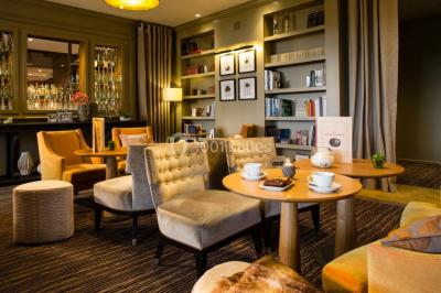 Salle lumineuse avec une grande table dressée, plafond végétalisé, canapés colorés et équipements de détente.