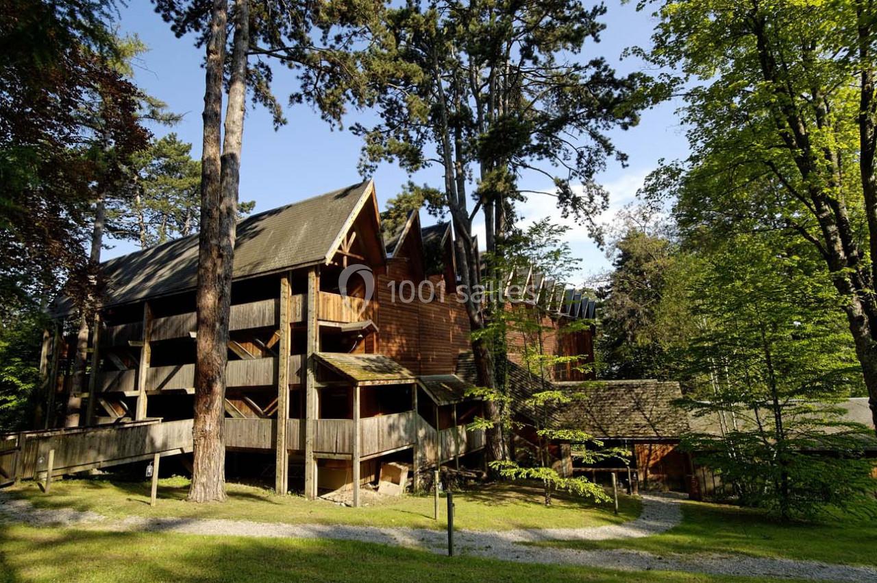Bâtiment en bois entouré d'arbres dans un environnement verdoyant sous un ciel dégagé.