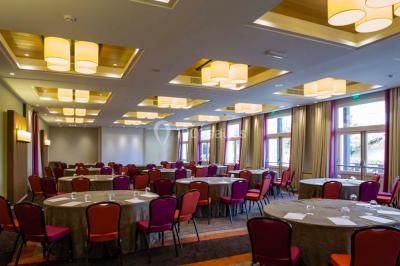 Salle lumineuse avec une grande table dressée, plafond végétalisé, canapés colorés et équipements de détente.