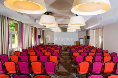 Salle lumineuse avec une grande table dressée, plafond végétalisé, canapés colorés et équipements de détente.