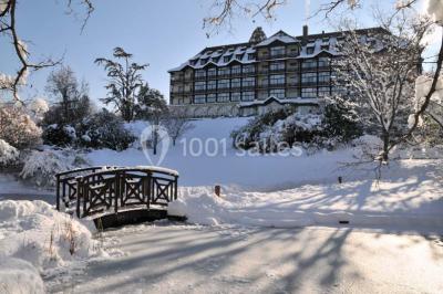 Salle lumineuse avec une grande table dressée, plafond végétalisé, canapés colorés et équipements de détente.