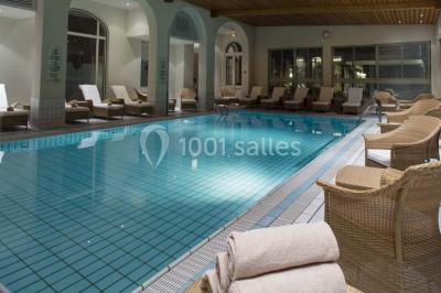 Salle lumineuse avec une grande table dressée, plafond végétalisé, canapés colorés et équipements de détente.