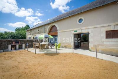 Chambre lumineuse avec lit double, rideaux transparents, plafond en poutres apparentes et vue sur une terrasse ensoleillée.