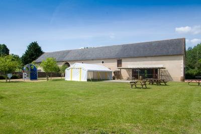 Chambre lumineuse avec lit double, rideaux transparents, plafond en poutres apparentes et vue sur une terrasse ensoleillée.