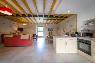 Chambre lumineuse avec lit double, rideaux transparents, plafond en poutres apparentes et vue sur une terrasse ensoleillée.