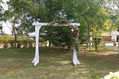 Chambre lumineuse avec lit double, rideaux transparents, plafond en poutres apparentes et vue sur une terrasse ensoleillée.