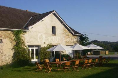 Aménagement de jardin avec un parterre circulaire entouré de pierres, contenant des plantes, sur fond de verdure et collines.