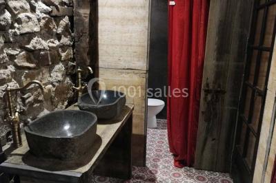 Aménagement de jardin avec un parterre circulaire entouré de pierres, contenant des plantes, sur fond de verdure et collines.