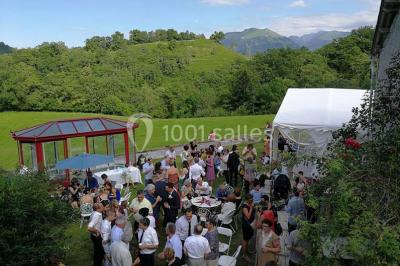 Aménagement de jardin avec un parterre circulaire entouré de pierres, contenant des plantes, sur fond de verdure et collines.