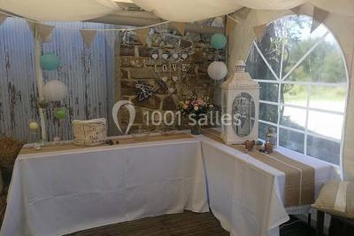 Aménagement de jardin avec un parterre circulaire entouré de pierres, contenant des plantes, sur fond de verdure et collines.