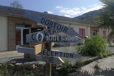 Aménagement de jardin avec un parterre circulaire entouré de pierres, contenant des plantes, sur fond de verdure et collines.