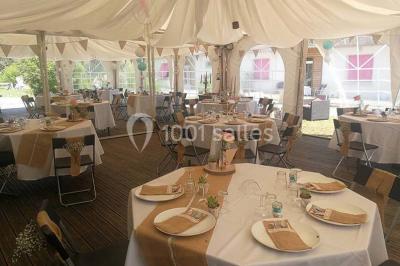 Aménagement de jardin avec un parterre circulaire entouré de pierres, contenant des plantes, sur fond de verdure et collines.