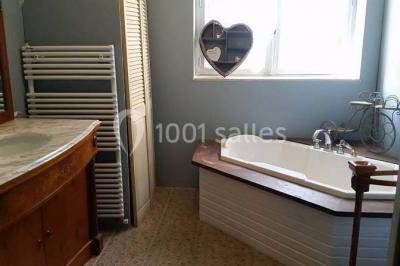 Aménagement de jardin avec un parterre circulaire entouré de pierres, contenant des plantes, sur fond de verdure et collines.