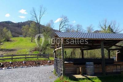 Aménagement de jardin avec un parterre circulaire entouré de pierres, contenant des plantes, sur fond de verdure et collines.