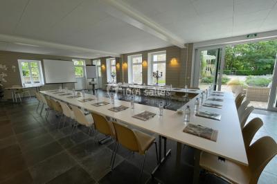 Façade d'un bâtiment en pierre de style classique avec tourelle, entouré d'une grille en fer forgé et d'un jardin.