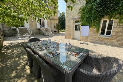 Façade d'un bâtiment en pierre de style classique avec tourelle, entouré d'une grille en fer forgé et d'un jardin.