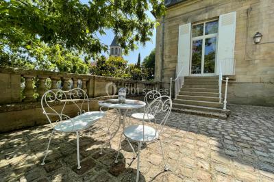 Façade d'un bâtiment en pierre de style classique avec tourelle, entouré d'une grille en fer forgé et d'un jardin.