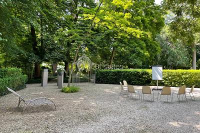Façade d'un bâtiment en pierre de style classique avec tourelle, entouré d'une grille en fer forgé et d'un jardin.