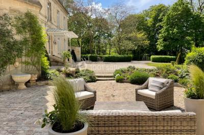 Façade d'un bâtiment en pierre de style classique avec tourelle, entouré d'une grille en fer forgé et d'un jardin.