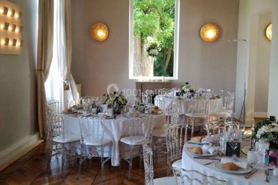 Façade d'un bâtiment en pierre de style classique avec tourelle, entouré d'une grille en fer forgé et d'un jardin.