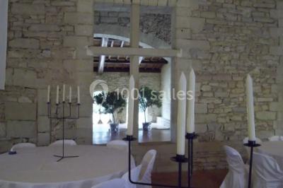 Terrasse en pierre spacieuse devant un bâtiment ancien en pierre sous un ciel bleu dégagé.