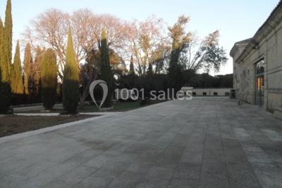 Terrasse en pierre spacieuse devant un bâtiment ancien en pierre sous un ciel bleu dégagé.