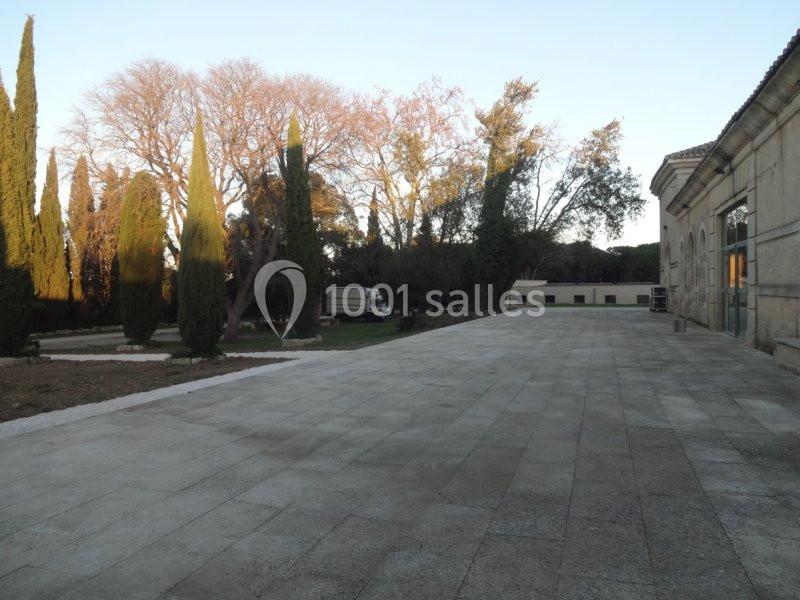 Allée pavée bordée d'arbres et de bâtiments anciens sous un ciel dégagé en fin de journée.