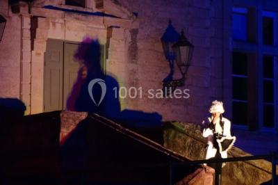 Terrasse en pierre spacieuse devant un bâtiment ancien en pierre sous un ciel bleu dégagé.