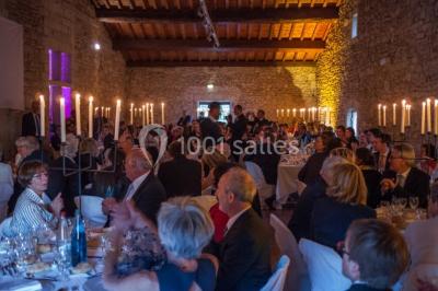 Terrasse en pierre spacieuse devant un bâtiment ancien en pierre sous un ciel bleu dégagé.