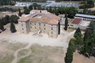 Terrasse en pierre spacieuse devant un bâtiment ancien en pierre sous un ciel bleu dégagé.