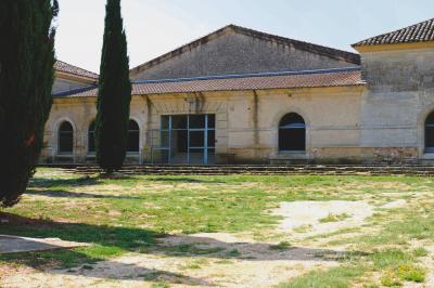 Terrasse en pierre spacieuse devant un bâtiment ancien en pierre sous un ciel bleu dégagé.