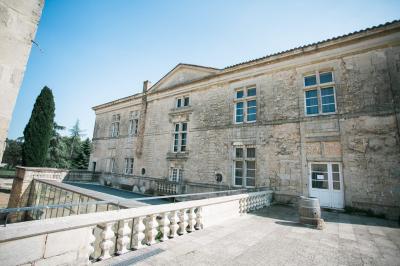 Terrasse en pierre spacieuse devant un bâtiment ancien en pierre sous un ciel bleu dégagé.