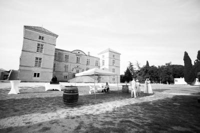 Terrasse en pierre spacieuse devant un bâtiment ancien en pierre sous un ciel bleu dégagé.