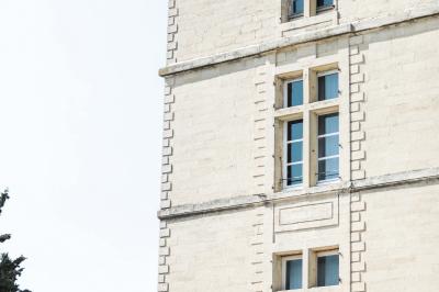 Terrasse en pierre spacieuse devant un bâtiment ancien en pierre sous un ciel bleu dégagé.