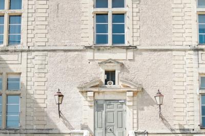 Terrasse en pierre spacieuse devant un bâtiment ancien en pierre sous un ciel bleu dégagé.