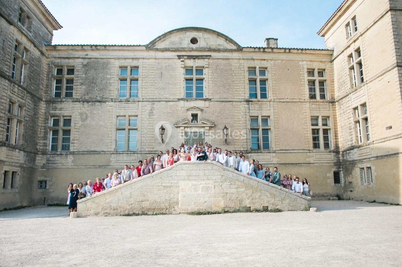 Groupe de personnes posant sur un escalier en pierre devant un grand bâtiment historique en journée.