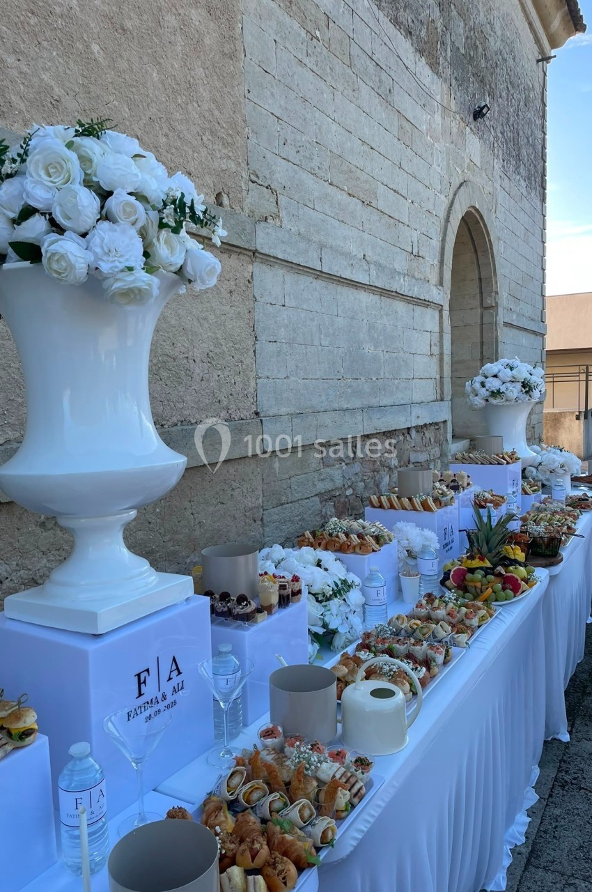 Table de buffet en extérieur avec des fleurs blanches en décoration, garnie de plats variés et de fruits.