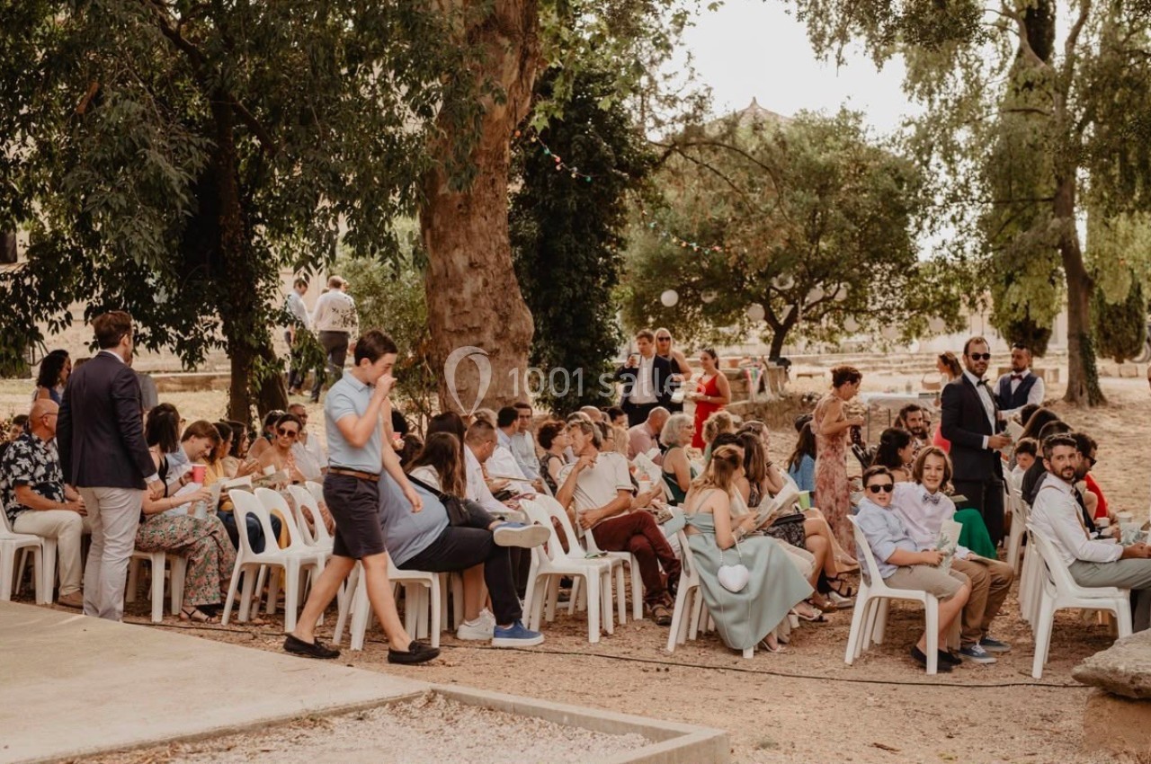 Groupe de personnes assises en extérieur lors d'un événement, entourées d'arbres et de décorations festives.