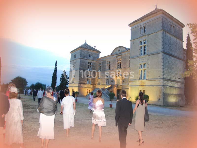 Groupe de personnes marchant vers un château éclairé en soirée, entouré d'arbres et d'un ciel dégagé.