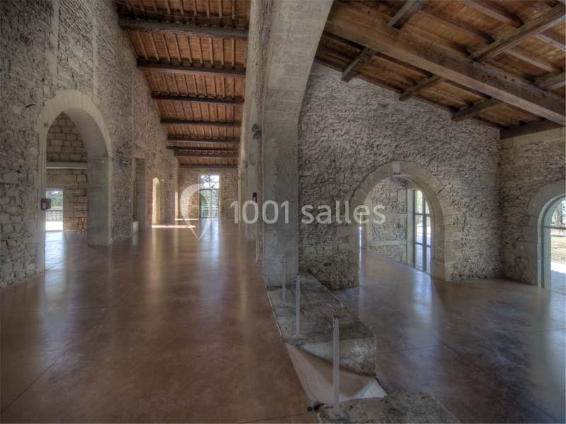 Intérieur d'un bâtiment en pierre avec des arches, un sol en béton poli et un plafond en bois.