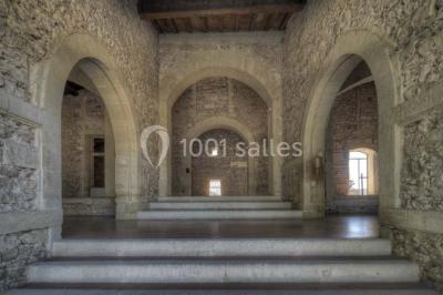 Terrasse en pierre spacieuse devant un bâtiment ancien en pierre sous un ciel bleu dégagé.